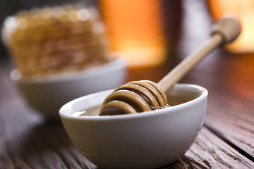Honey in jar with honey dipper on wooden background 