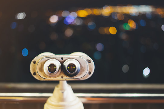 Touristic telescope look at city with view of Barcelona Spain, close up metal binoculars on background viewpoint, hipster coin operated in panorama observation, illumination bokeh light in night blur 