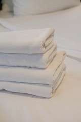 Fototapeta na wymiar Stack of towels on a bed in a hotel room
