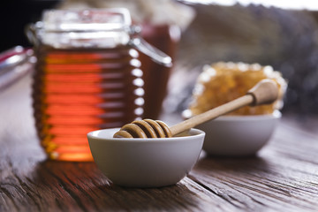 Honey in jar with honey dipper on wooden background 
