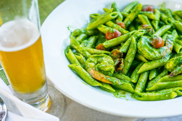 Vegetable penne pasta in basilica sauce with tomatoes decorated with parsley on a wooden table in restaurant