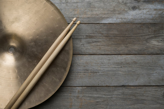 Drum stick and crash cymbal on wood table background, top view, music concept