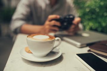 Young man photographer taking picture sitting at table in coffee shop