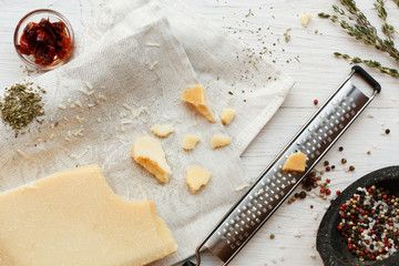 Parmesan piece with small grater and herbs top view