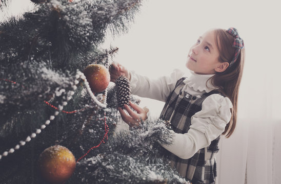 Pretty little girl decorate big christmas tree