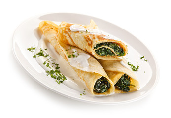 Crepes with spinach and feta cheese on white background