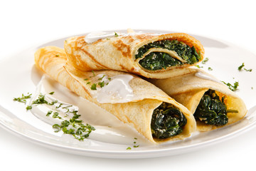 Crepes with spinach and feta cheese on white background