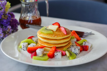 Pancakes for breakfast topped with strawberry and kiwi