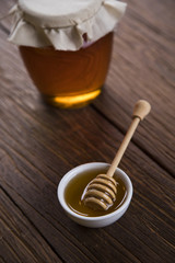 Honey in jar with honey dipper on wooden background 
