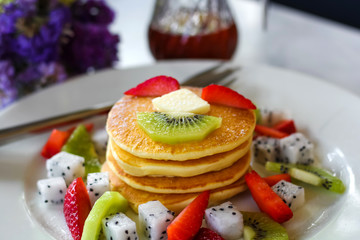 Pancakes for breakfast topped with strawberry and kiwi
