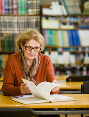 Senior woman reading book in library