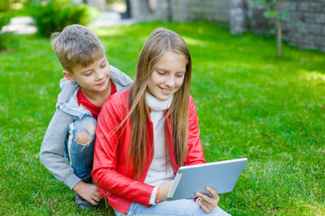 children communicate using a tablet computer on green grass
