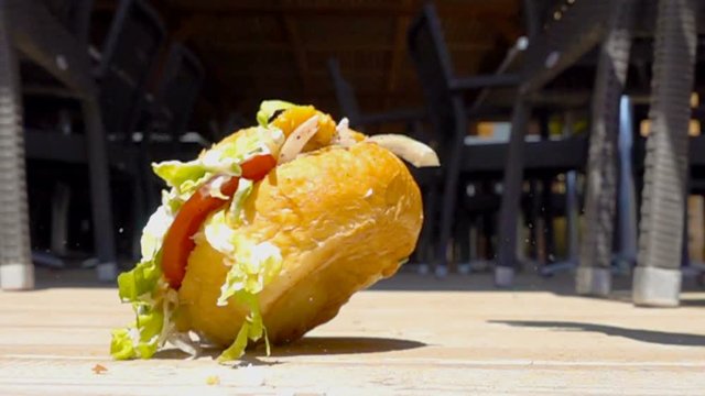 on sunny day hamburger with sauce falls to floor in cafe, slow motion