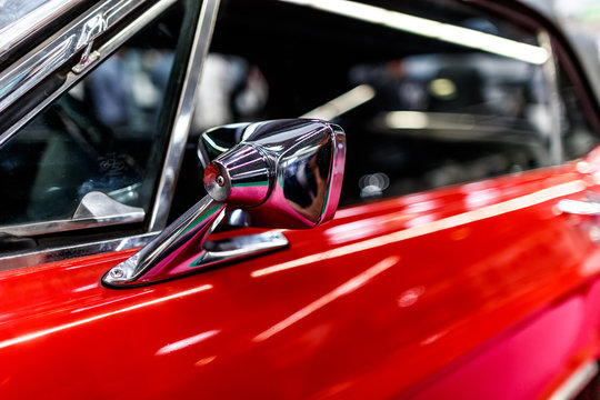 chrome rear-view mirror by the red sports vintage car.