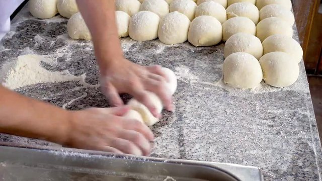 chef puts raw dough in container in kitchen