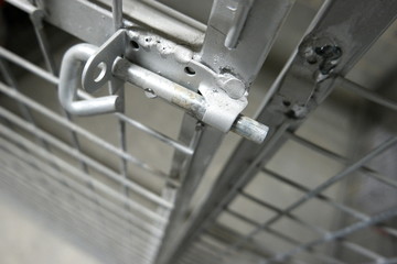 Unlocked gate of a metal storage cage with wire netting