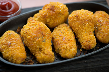 Close-up of fried breaded chicken wings served with sauce, selective focus