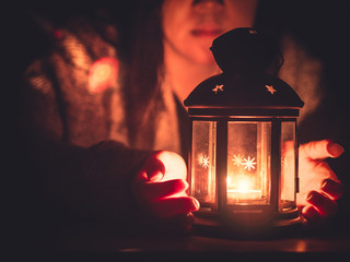 candle light and black lantern with soft focus background girl(25s to 35s) in the winter cloth pray in christmas night © tickcharoen04