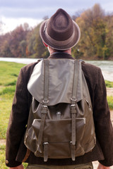 backside of bavarian man with backpack standing by river