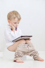 toddler sitting on chamber pot playing tablet pc