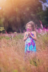 Joyful girl on a summer windy day with a bouquet of flowers