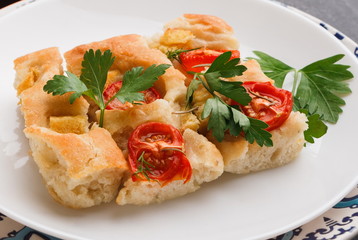 Casserole with tomatoes and greens on a white plate.
