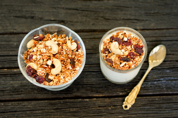 Granola with cashew and glass with yoghurt on dark wooden background