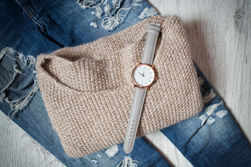 Stylish clock on a sweater and torn jeans. Fashionable concept