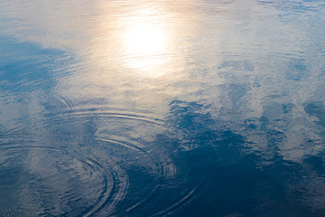 Water wave with reflection of clouds and sunset
