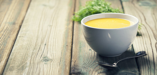 Vegetable cream soup in bowl over old wooden background