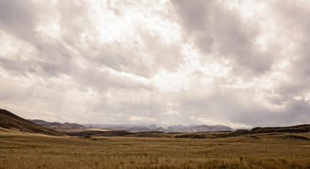 Western Plains Landscape with a Stormy Sky and Rocky Mountains in the Background