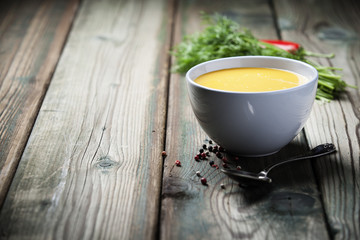 Vegetable cream soup in bowl over old wooden background