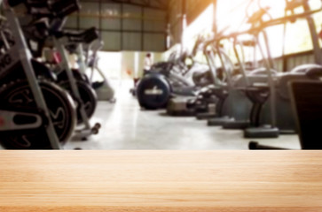 Wooden table on blurred background of fitness gym interior of modern club with equipment for your photomontage or product display.