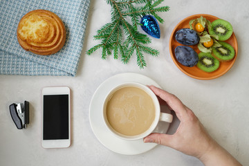 New Year's still life in the office. Bun, coffee with milk, calculator, hand holding a cup with a coffee.