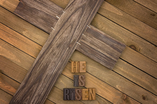 He is Risen Spelled on a Wooden Table with a Cross
