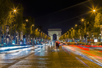 Fototapeta na wymiar Illuminated Arc de Triomphe and the avenue Champs-Elysees in Paris. Famous touristic places and transportation concept. Night urban landscape with street traffic and city lights. Long exposure. Toned