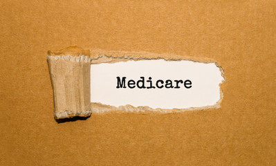 The text Medicare appearing behind torn brown paper