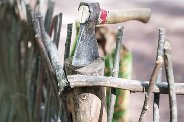 The old axe in the chopping block at the wooden fence