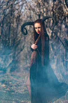 beautiful woman dressed as a fairy witch in raincoat and with horns for Halloween