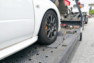 Car towed onto flatbed tow truck with hook and chain