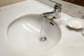 Modern hygienic wash basin with running water from tap faucet