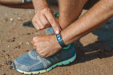 male athlete checking calories burned in smart wristband at the seashore in summer