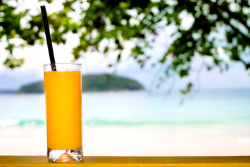 Glass of fresh cold mango juice on sea view blur background.