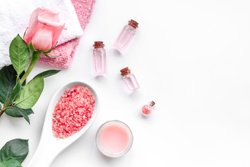 Spa products with rose oil. Cream, lotion and salt on white background top view copyspace
