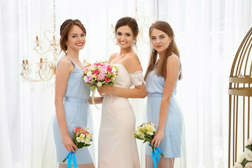 Happy beautiful bride with bridesmaids on wedding day, indoors