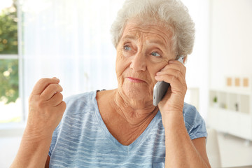 Elderly woman speaking on cell phone at home