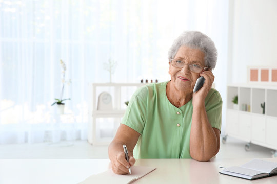 Elderly woman speaking on cell phone at home