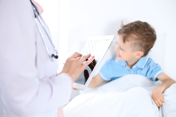 Fototapeta premium Female doctor using a digital tablet, close-up of hands. Health care concept or children's therapy 