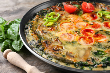 Frying pan with delicious spinach frittata on table, closeup