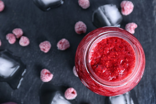 Glass jar with raspberry smoothie on dark background